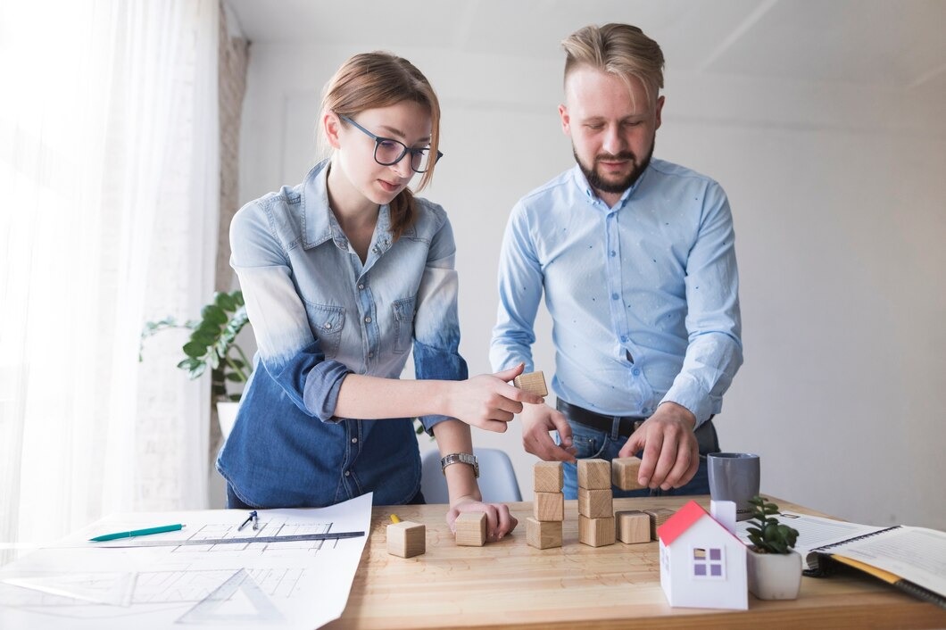 A man and woman collaboratively assembling colorful building blocks on a table, focused on their task