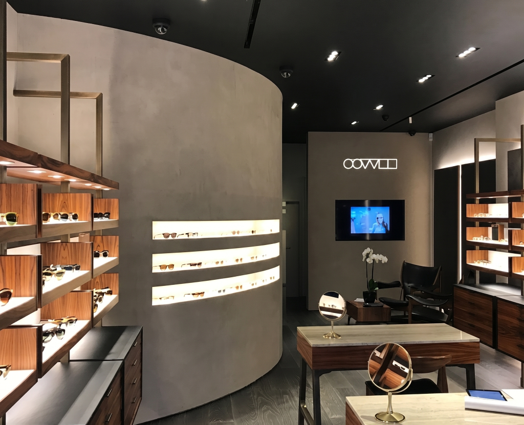 Modern luxury eyewear store interior featuring wooden display shelves with various sunglasses and elegant decor lighting